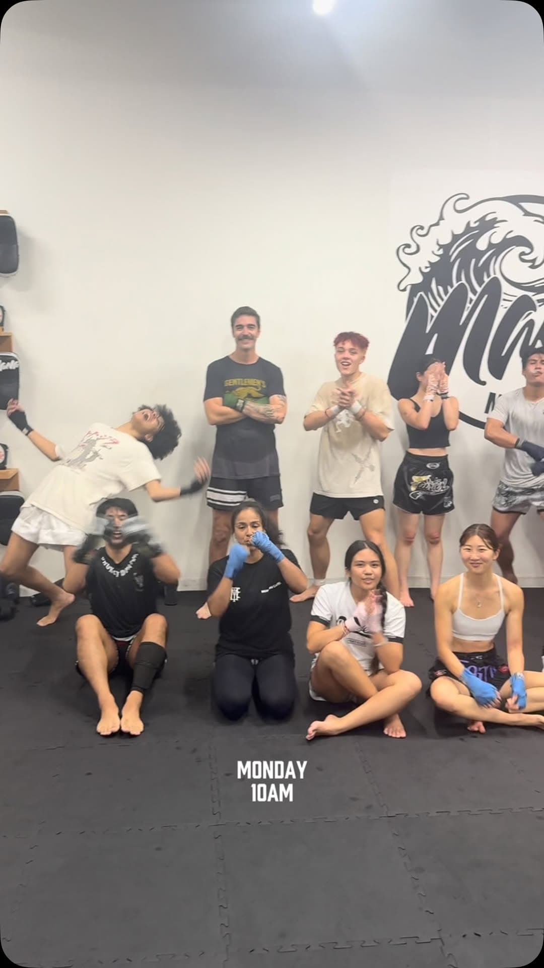 Class group photo in front of the wave mural after a Monday morning session