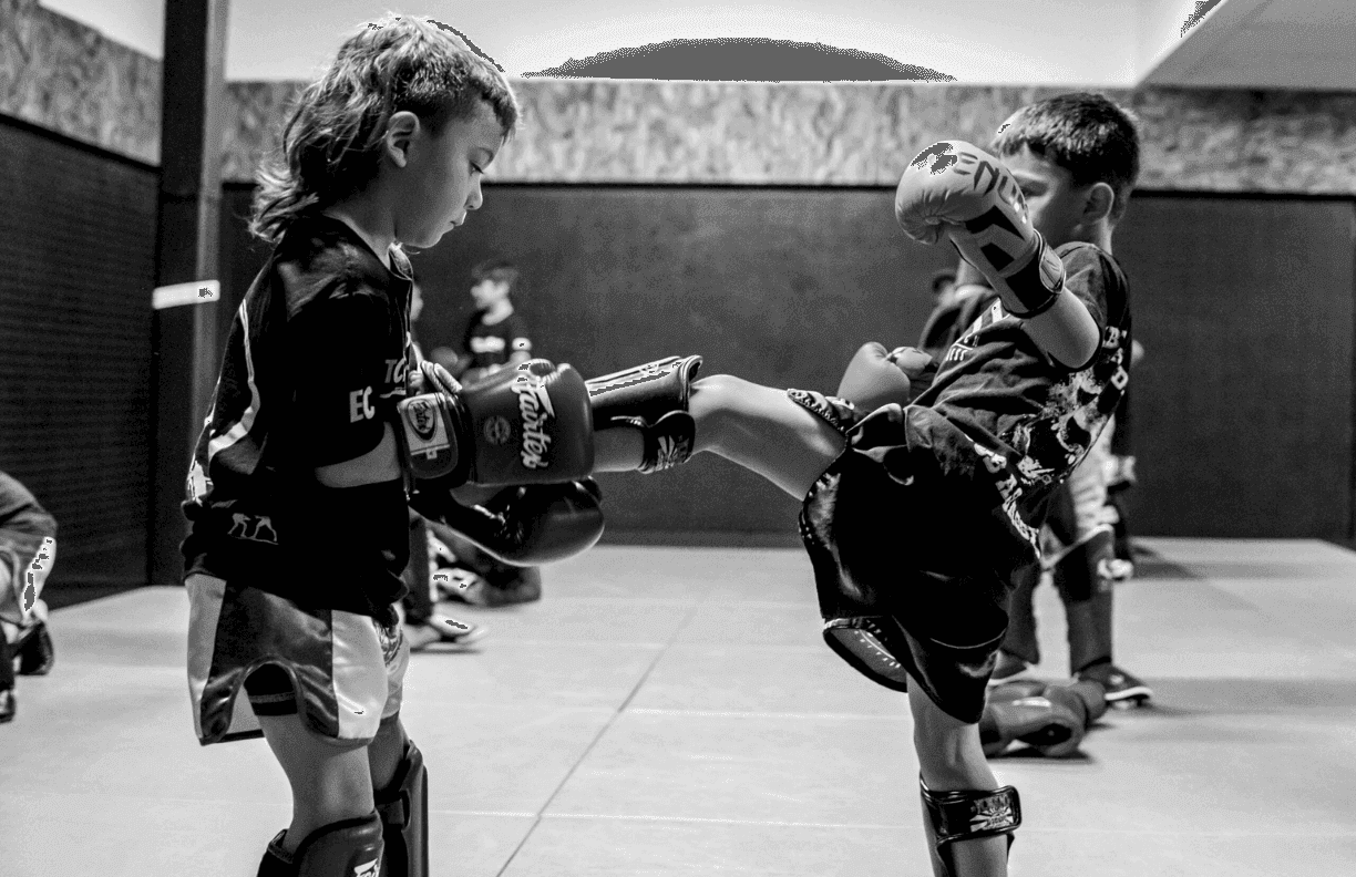 Two young students in gloves and shin guards training on the mats