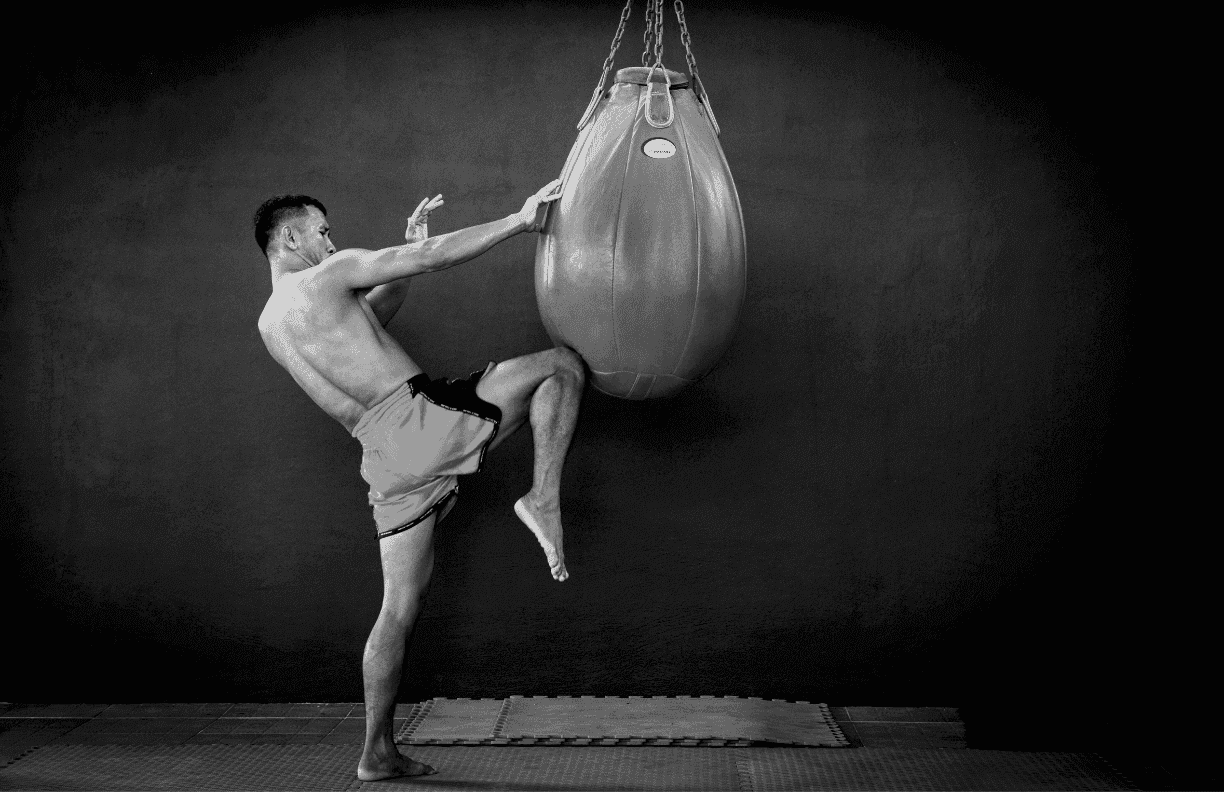 Athlete driving a knee into a hanging teardrop bag